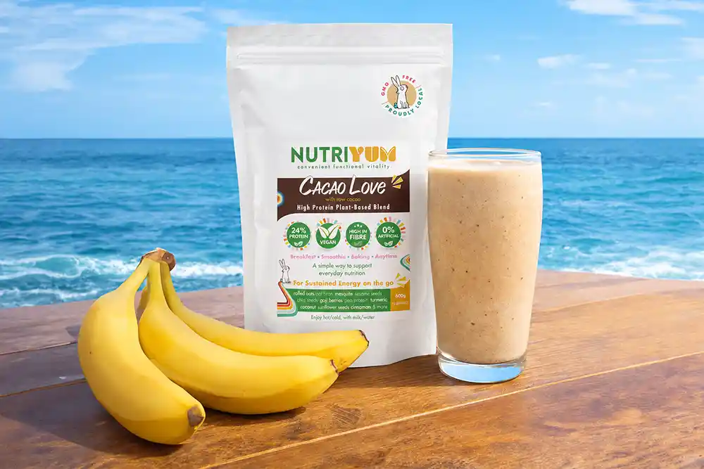 Vegan banana protein smoothie made with Nutriyum Cacao Love, next to the 600g pouch and fresh bananas
